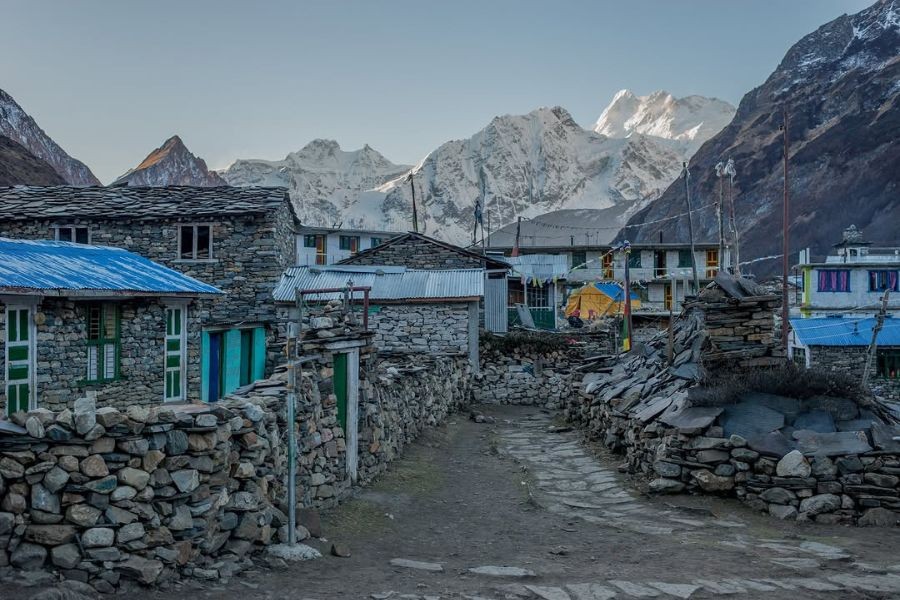 Himalayan village with traditional stone houses and glacier-covered mountains